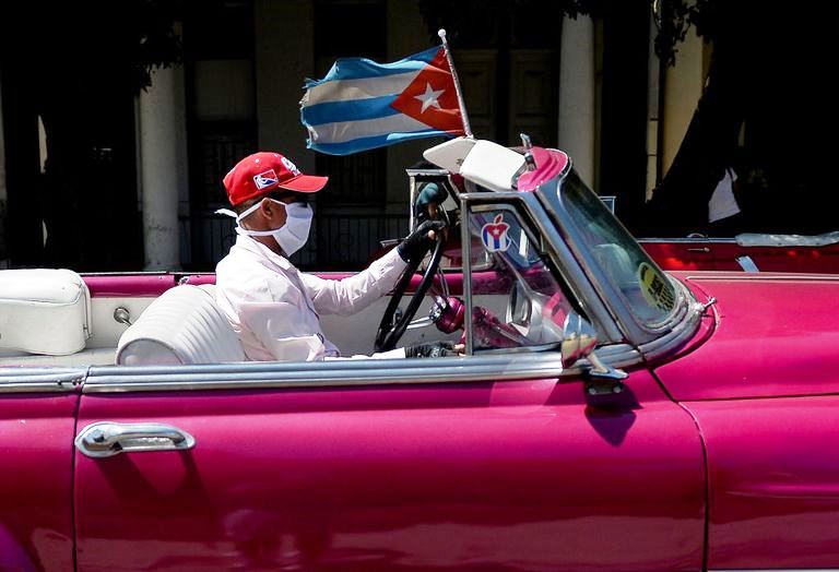 Hombre llevando nasobuco conduce coche restaurado de los años 1950